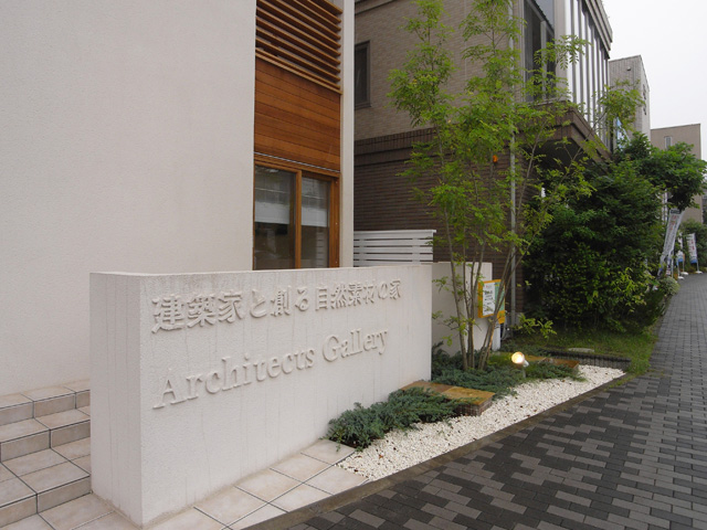 アプローチの建物と統一した広告機能を持った珪藻土の塀と石のボーダー、植栽。